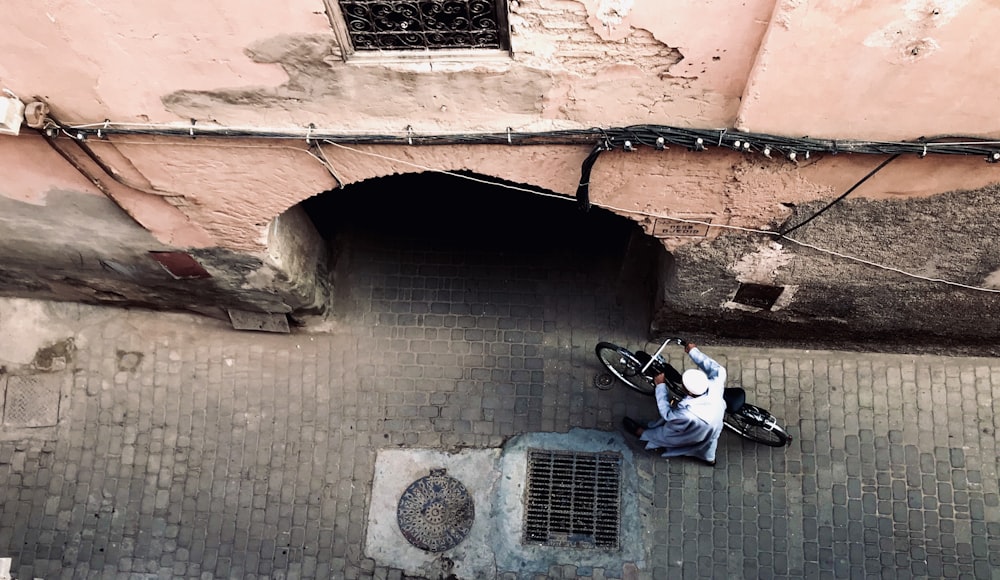 a person with a bike on a cobblestone street