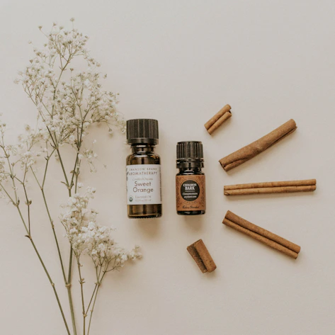 Close-up of amber essential oil bottles surrounded by fresh lavender and eucalyptus leaves on a wooden table.