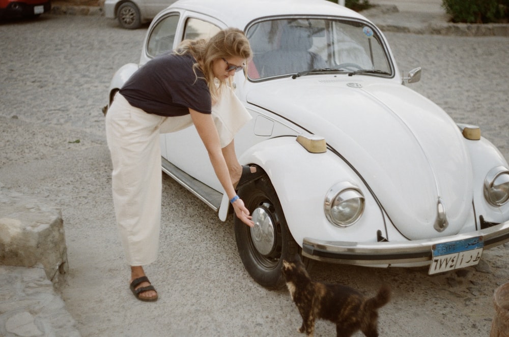 woman standing beside white Volkswagen Beetle