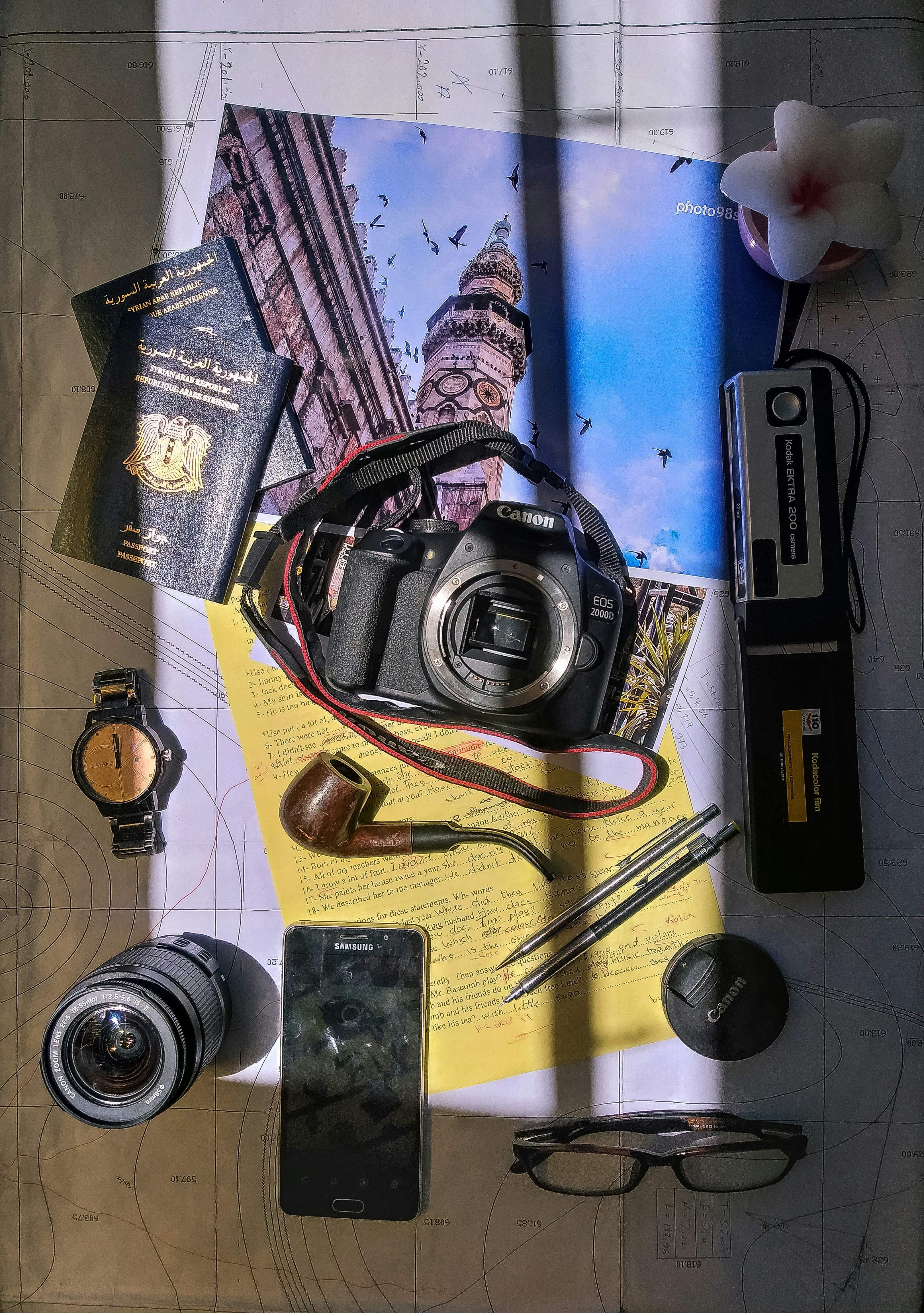 black digital camera in between of passport, tobacco pipe and round silver-colored analog watch
