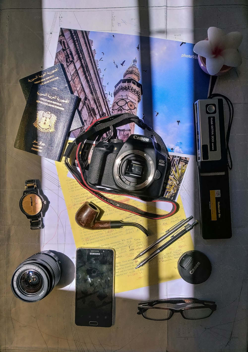 black digital camera in between of passport, tobacco pipe and round silver-colored analog watch