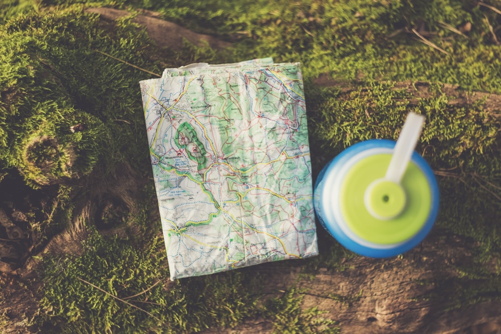 blue and green plastic bottle beside map on ground