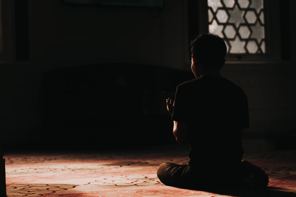 low-light photo of man sitting on the floor