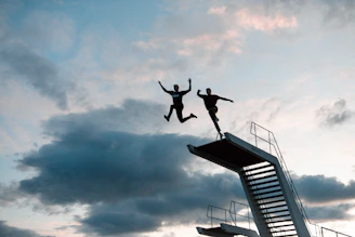 two person about to jump of swimming pool diving board
