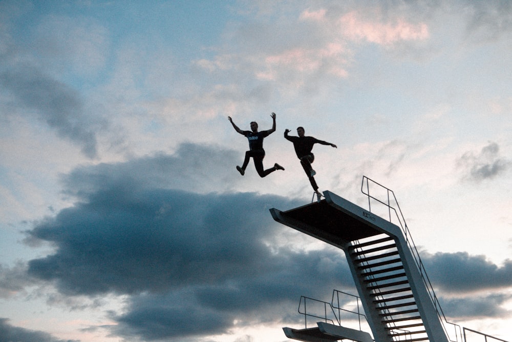 two person about to jump of swimming pool diving board