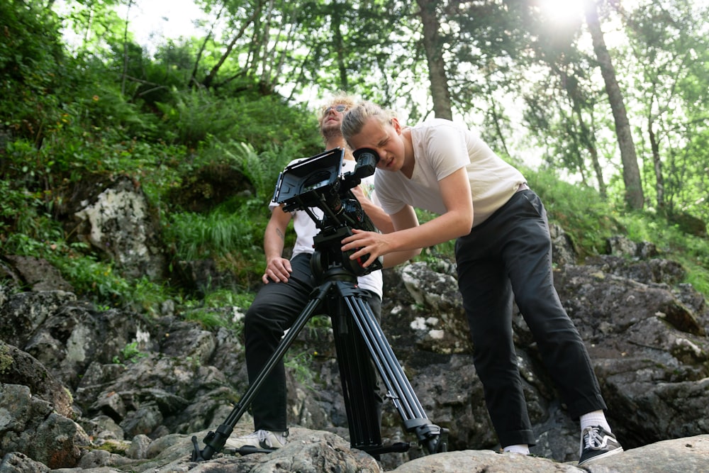 two men doing video recording while standing on rocks