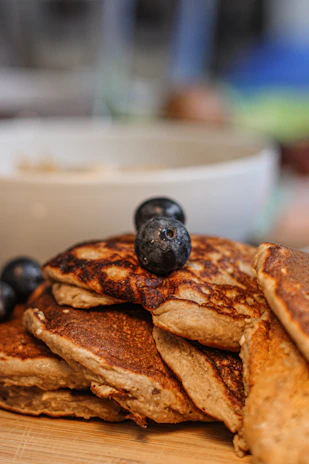 A close-up of a golden, fluffy pancake topped with fresh berries and a drizzle of honey, highlighting the wholesome texture.
