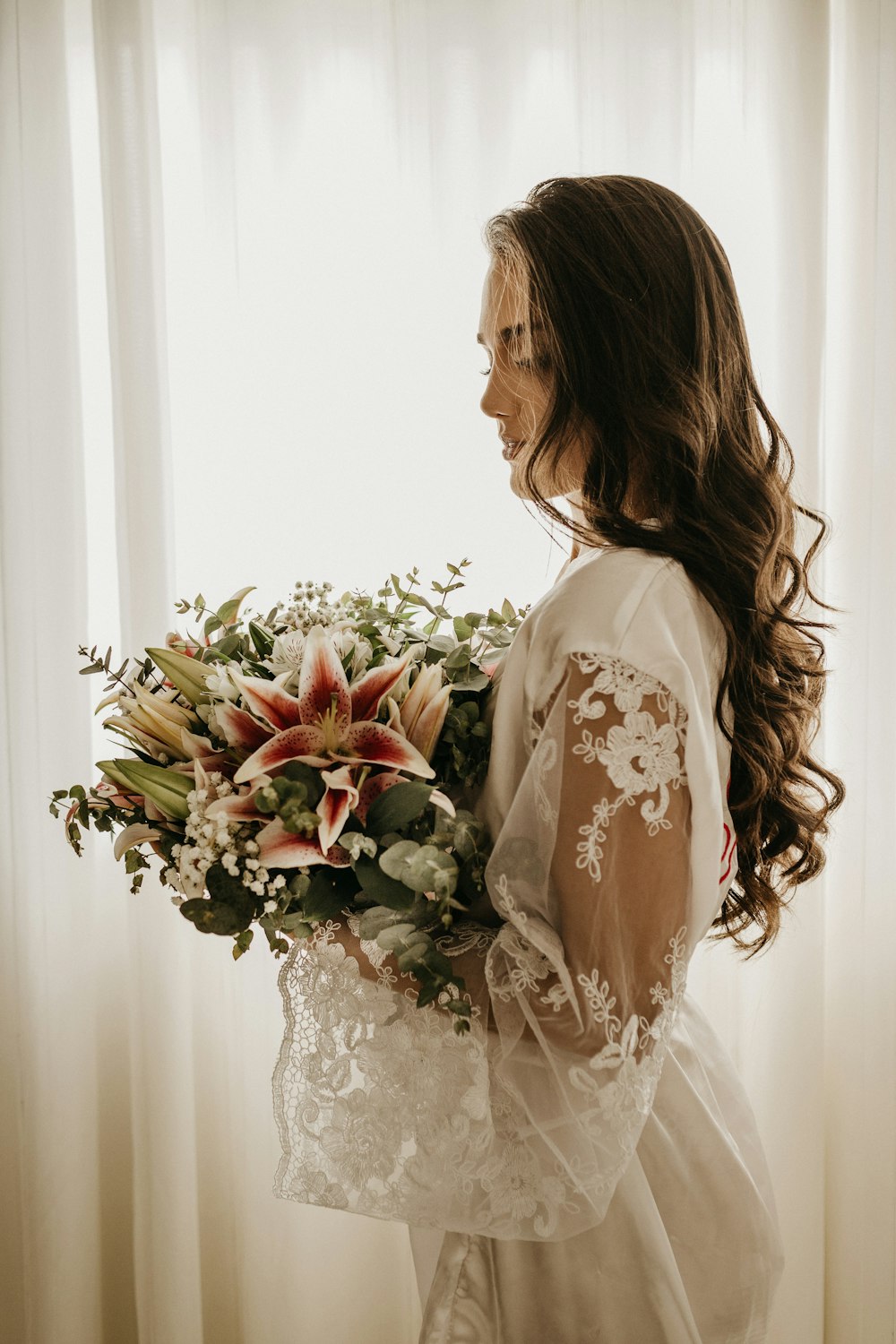 mujer en vestido blanco sosteniendo ramo de flores