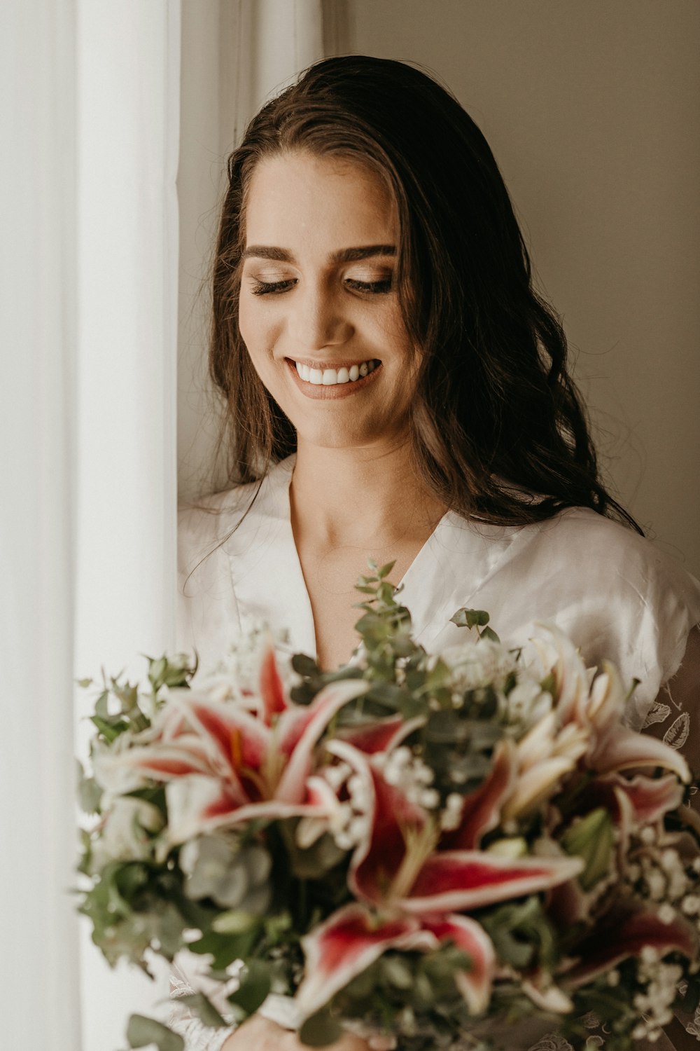 woman in white top holding bouquet of flowers