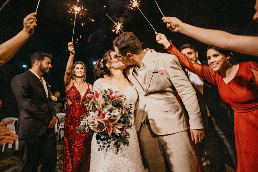 Newlyweds kissing under a sparkler arch held by their wedding party