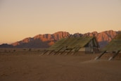 A row of custom-designed accommodation portacabins set against a desert backdrop at sunset.