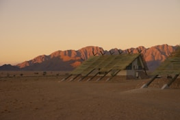 A row of custom-designed accommodation portacabins set against a desert backdrop at sunset.
