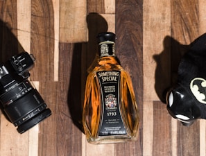 A quirky shot of a Scotch bottle wearing a tiny tartan hat beside a plate of smoked salmon