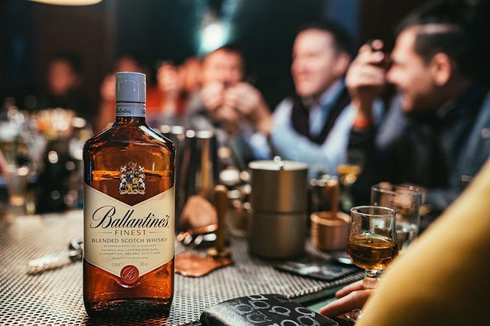 Ballantines Flasche auf grauer Oberfläche neben Becher