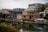 Houseboats are moored along a calm dock in front of modern apartment buildings, reflecting the urban residential setting. The water is still, and the lighting is soft, indicating a cloudy or overcast day.