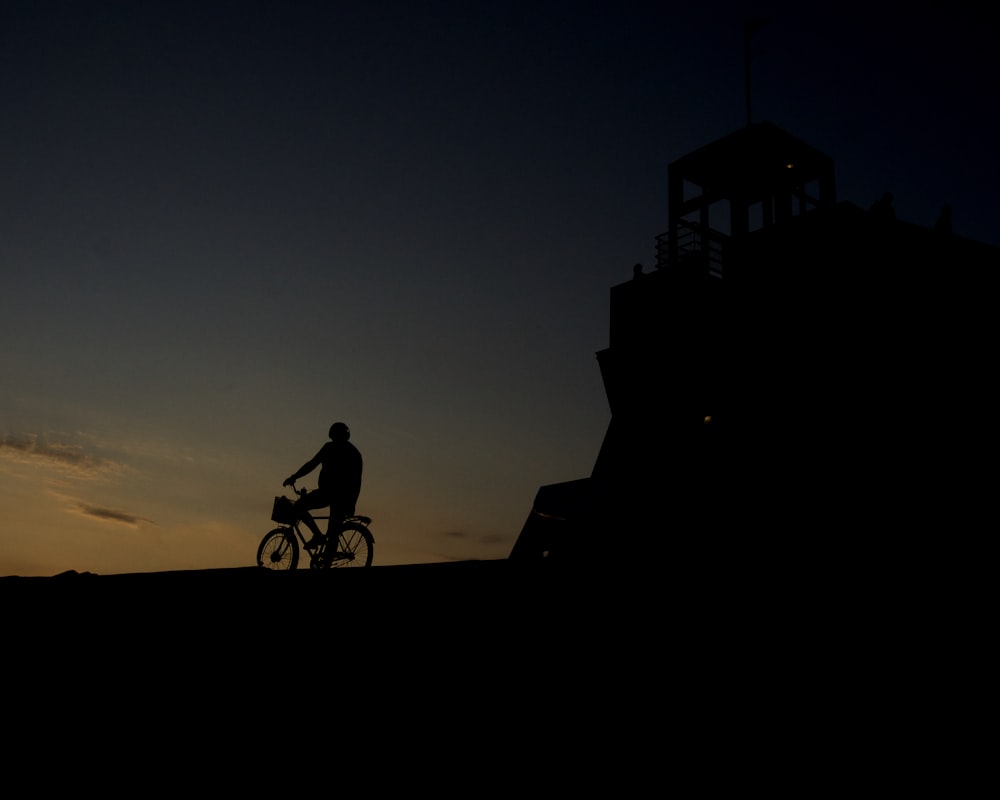 silhouette of person riding bicycle during golden hour