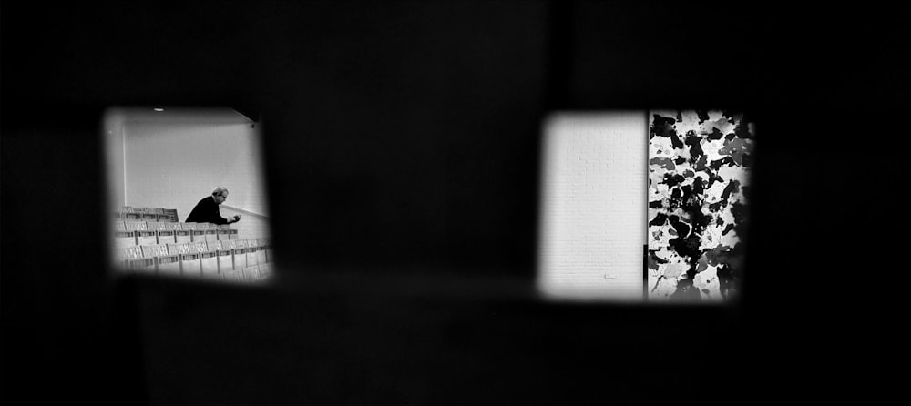 a black and white photo of a person sitting on a ledge