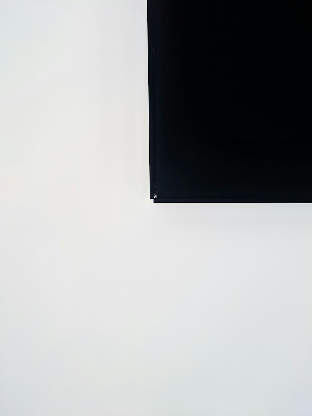 a white wall with a black piece of art hanging on it