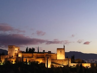 Historic fortress walls bathed in soft evening light, surrounded by rolling hills.