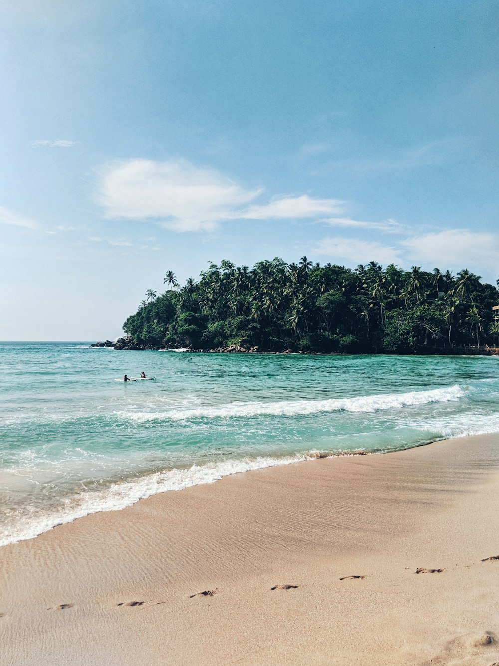 sea waves crashing on shore with island in distant