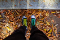 Casual sneakers with vibrant mismatched shoelaces standing on city pavement