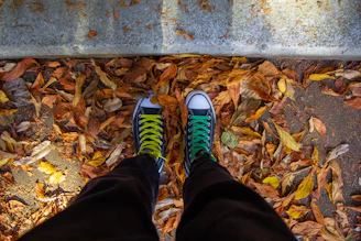 Casual sneakers with vibrant mismatched shoelaces standing on city pavement