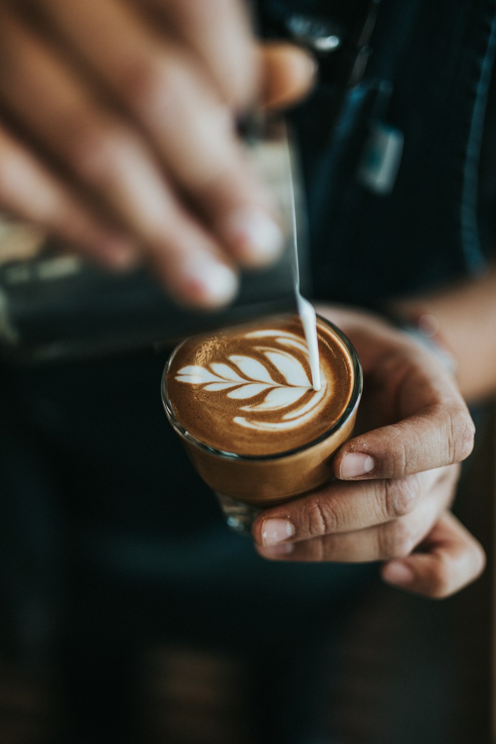 person pouring cream on coffee