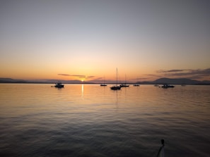 A peaceful sunset over the Douro River with boats gently floating and hills in the background.