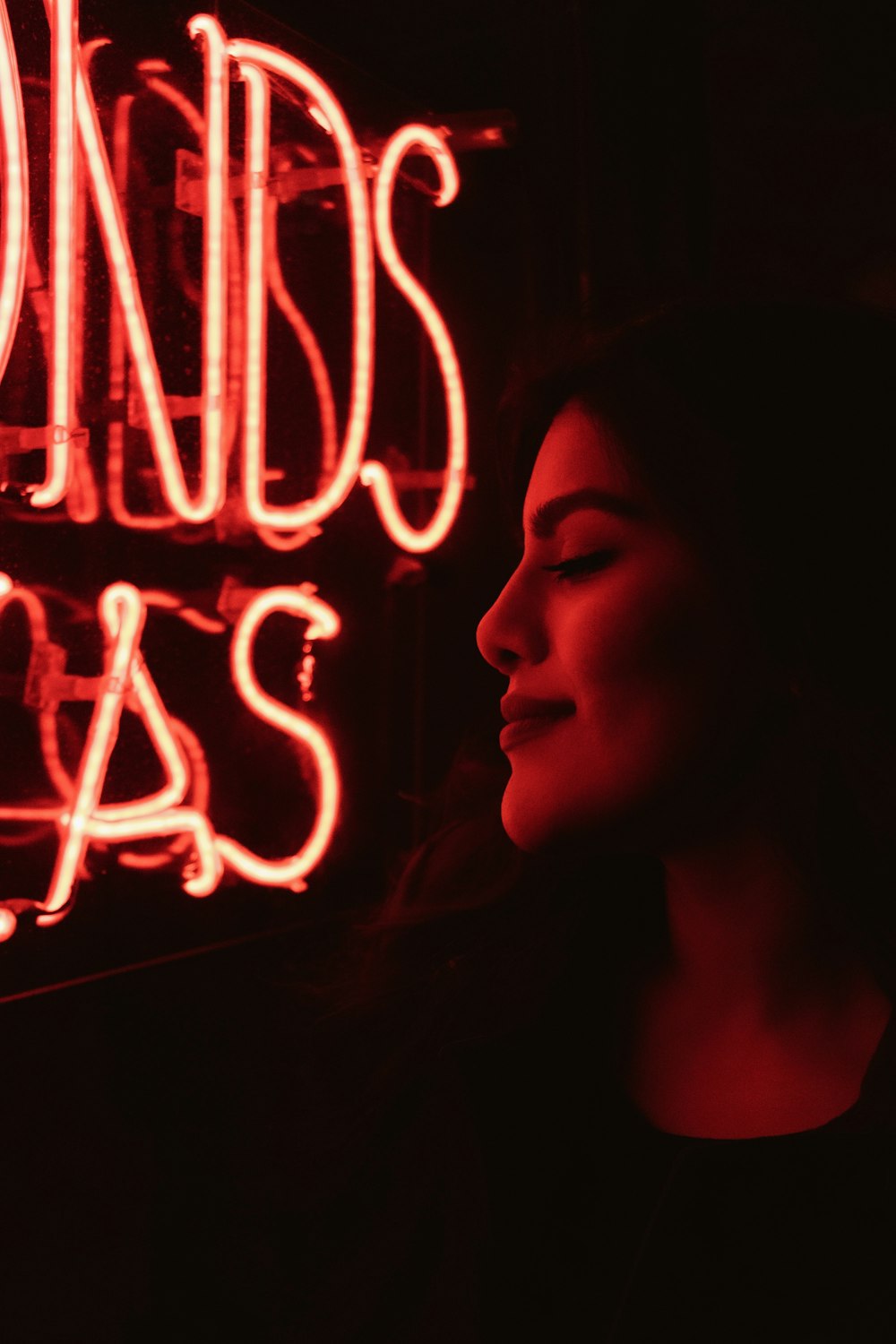 low-light photo of woman standing in front of neon sign