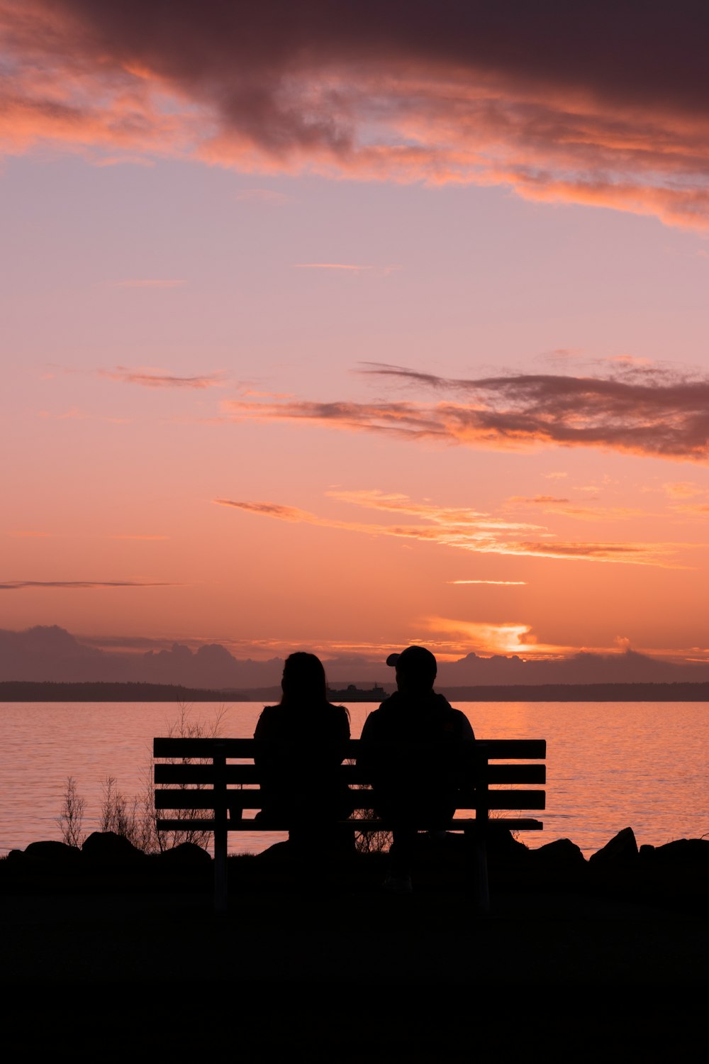 silhouette photography of man and woman sitting on bench during golden hour
