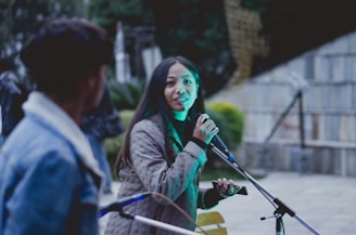 A journalist interviewing a community member outdoors with a microphone and notepad.