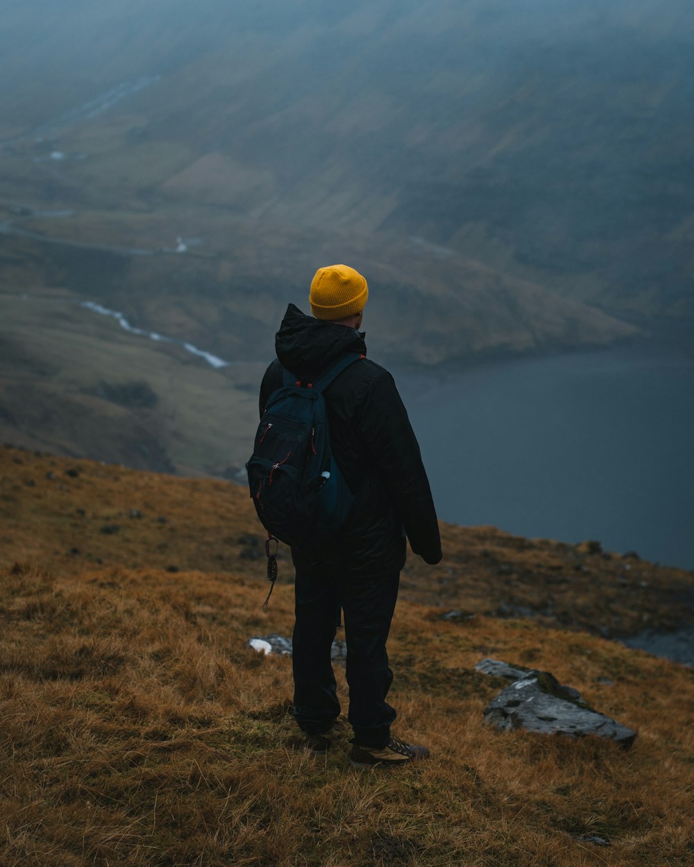 man in black hoodie standing on hill