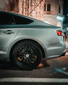 A modern car fitted with premium black and silver alloy wheels parked on a city street.