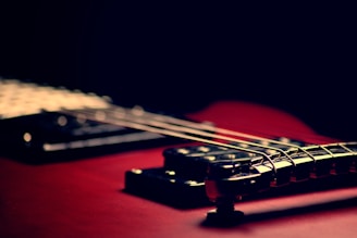 A close-up of an electric guitar’s strings and vibrant body under stage lights.