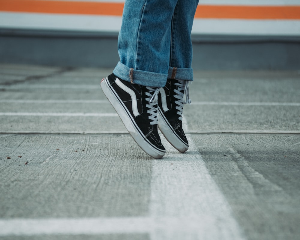 perrson wearing pair of black VANS shoes