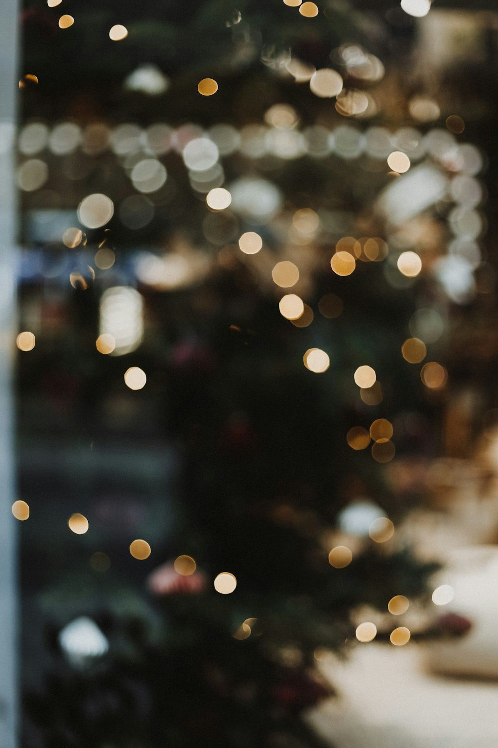 a blurry christmas tree is seen through a window