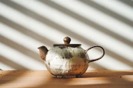 A cozy corner with a handmade ceramic teapot and cup, sunlight casting soft shadows.
