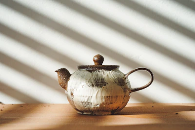 Sunlight casting soft shadows over a colorful ceramic teapot and matching cups.