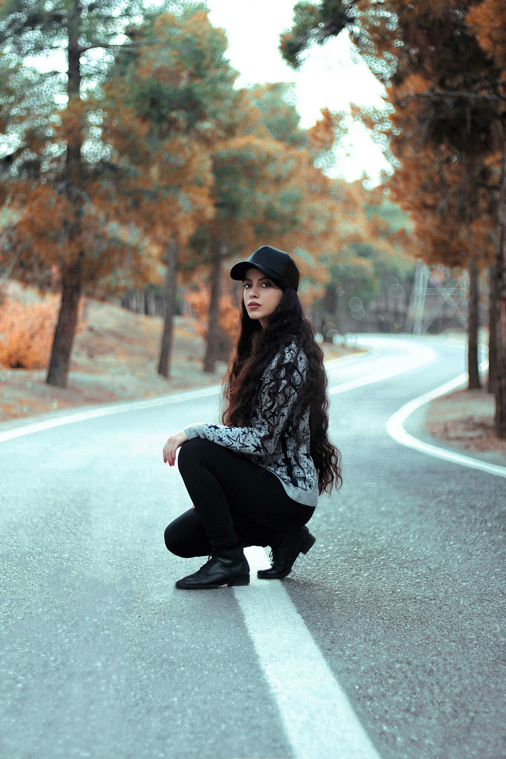 woman squatting on middle of road during daytime