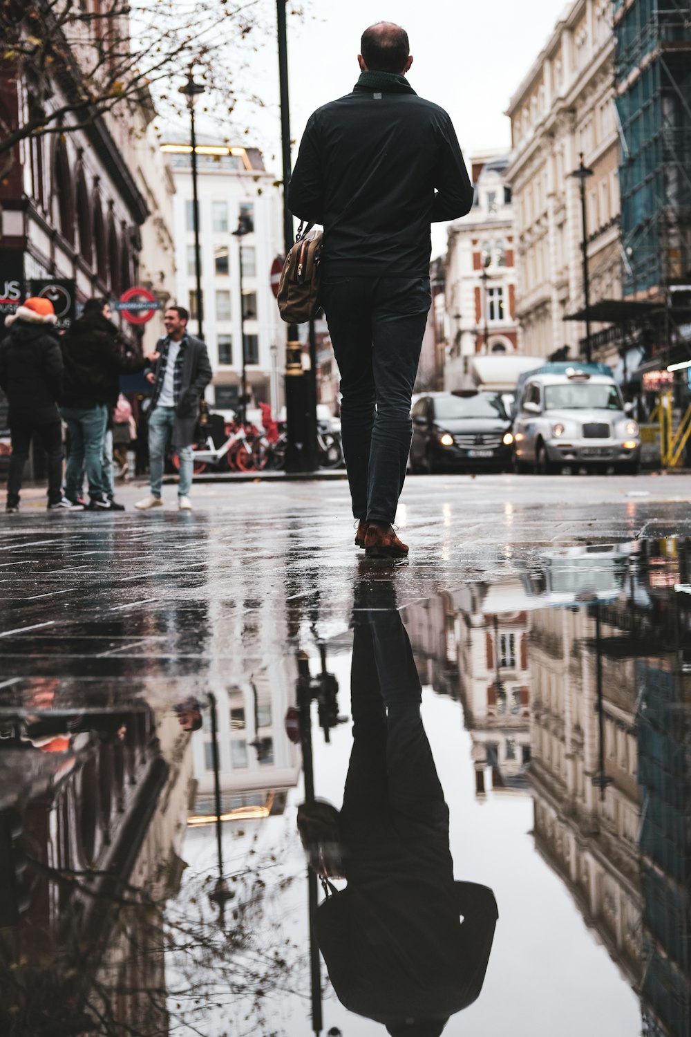 man wearing black long-sleeved shirt walking on wet road