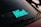 A car windshield with a bold mint-colored sticker displaying the word 'Mint.' The windshield wipers are visible, and there is a dark ambiance surrounding the car.