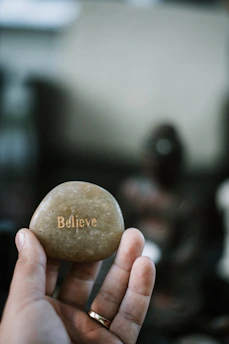 Close-up of hands holding a smooth stone with the word 'clarity' engraved on it.
