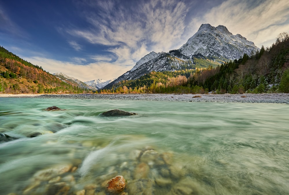 rock underwater facing mountain under blue sky