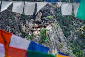 A peaceful Buddhist monastery perched on a cliff with prayer flags fluttering in the breeze.