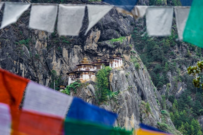 Ancient monastery perched on a cliff with prayer flags fluttering in the breeze.