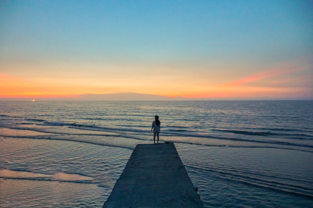 a person standing on a pier looking out at the ocean