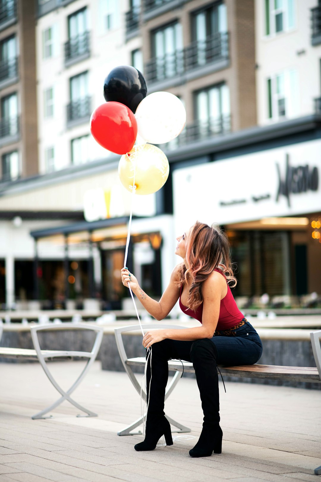 woman sitting on bench holding floating balloons