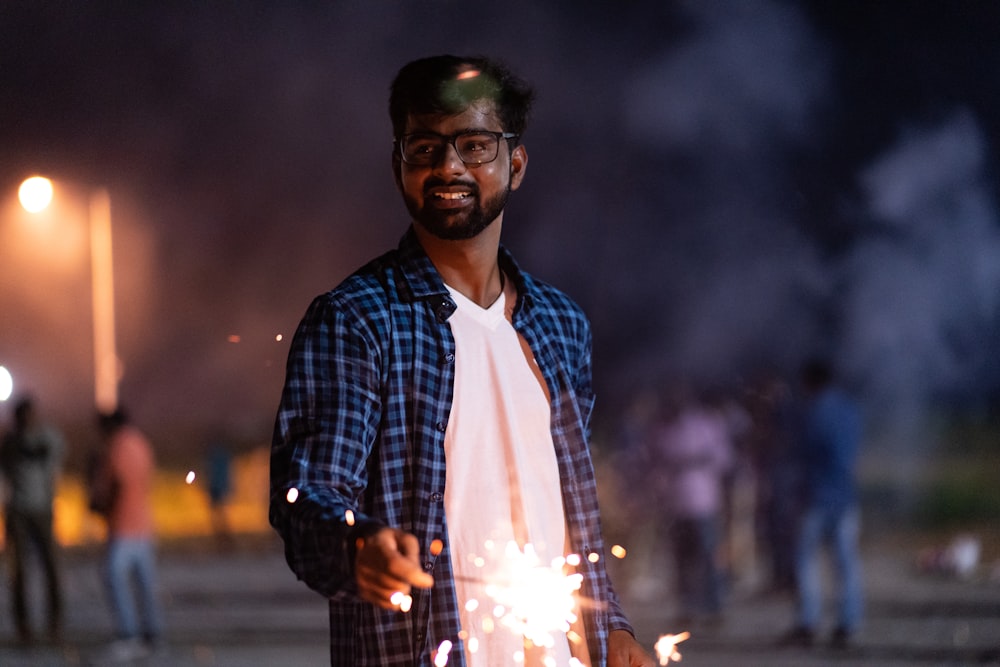 man holding lightened sparkler outdoor at night