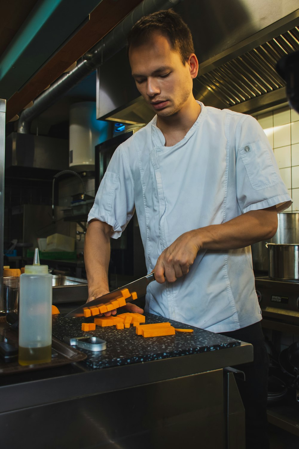 man wearing white shirt slicing inside kitchen