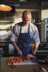 man slicing orange carrots